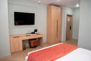 a bedroom with a bed and a desk with a television at Terrenkur boutique-hotel in Almaty