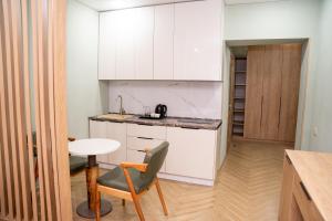a kitchen with white cabinets and a table and a chair at Terrenkur boutique-hotel in Almaty