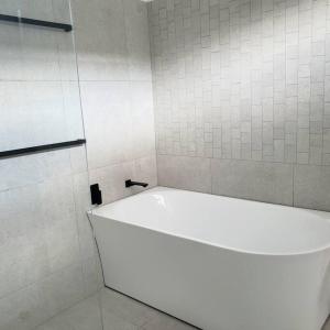 阿米代尔Boutique Cottage on Mann的白色瓷砖浴室内的白色浴缸 更多16张照片