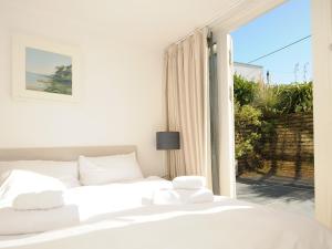 Un dormitorio con dos camas blancas y una ventana. en Drishti, en Polzeath