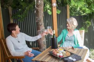 a man and woman sitting at a table with a glass of wine at Star Gaze From Your Bed in Fairlie