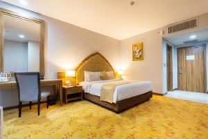 a hotel room with a bed and a desk and a chair at Grand Serela Yogyakarta in Yogyakarta +29 photos