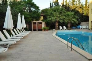 a swimming pool with lounge chairs and umbrellas next to a pool at Palm Court Suites in Ayvalık