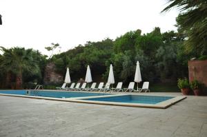 una piscina con sillas y sombrillas blancas en Palm Court Suites en Ayvalık