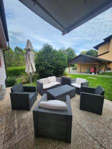 a patio with couches and an umbrella and a table and chairs at La Villa Joly - Avenches in Avenches