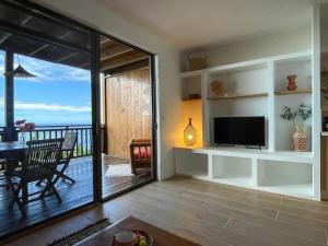 a living room with a television and a balcony at Taapuna SunSet Moorea View in Atiue