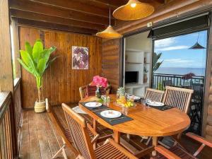 a dining room with a wooden table and chairs at Taapuna SunSet Moorea View in Atiue