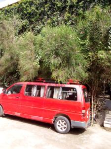 a red van parked in a parking lot with trees at GSF Guest House in Addis Ababa
