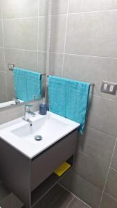 a bathroom with a sink and a mirror and blue towels at Departamento nuevo Santa Rosa del Mar, familiar, bien iluminado y cerca de todo, con estacionamiento gratis in Coquimbo
