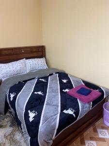 a bed with a black and white blanket with cows on it at Tsavo Apartments Ogembo Single Room in Ogembo