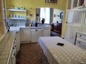 eine Küche mit weißen Schränken und einem Tisch darin in der Unterkunft L' Aphelide in Sablons-sur-Huisne