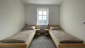 two beds in a room with a window at Apartmány Hvězdecká in Broumov
