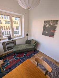 ein Wohnzimmer mit einem grünen Stuhl und einem Teppich in der Unterkunft Artistic 2-Bedroom full of light in Helsinki