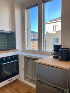 eine Küche mit zwei Fenstern und einer Theke mit einer Mikrowelle in der Unterkunft Artistic 2-Bedroom full of light in Helsinki