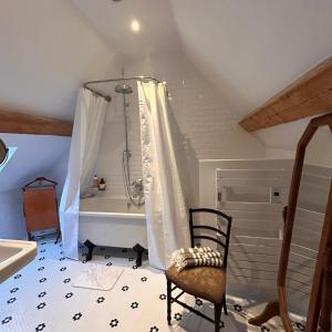 a bathroom with a bath tub and a chair at Le Domaine de Blanvatel in Sainte-Marguerite-de-Viette