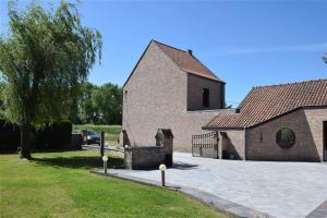 a large brick building with a tree and a driveway at Lichtrijke woning aan het Muziekbos in Ronse