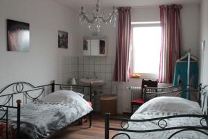 a bedroom with two beds and a sink and a window at Pension Rodenburg in Duppach