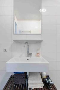a white sink in a white tiled bathroom at 120m2 Spacious 4-bedroom Apartment with Roofterras in Amsterdam +25 photos