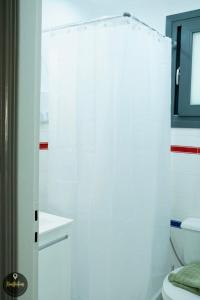 a bathroom with a white shower curtain and a toilet at Seaside Apartments in Emporeios