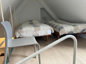 Una pequeña habitación con dos camas y una silla. en Studio Tintin, en Bruselas