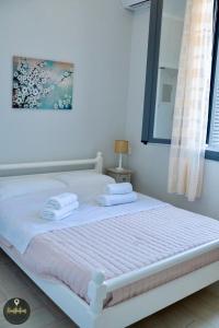 a white bed with two towels on top of it at Seaside Apartments in Emporeios