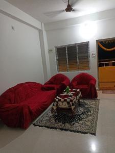Una sala de estar con dos sofás rojos y una mesa. en Skd heights, en Silchar