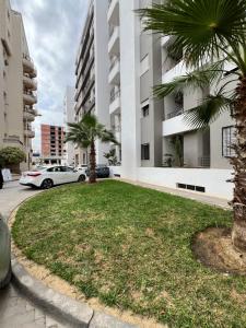 a grassy area with palm trees in front of a building at Location appartement luxueux Tunis in Tunis