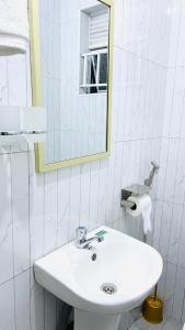 a white bathroom with a sink and a mirror at Spacious City Home in Kampala +27 photos