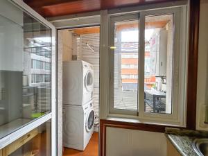 kuchnia z pralką i suszarką przy oknie w obiekcie Apartamento completo, amplio, muy iluminado y con plaza de garaje incluida. w mieście O Grove