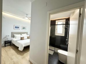a bedroom with a white bed and a bathroom at Alhóndiga City Center 105m By Sleep In Bilbao in Bilbao