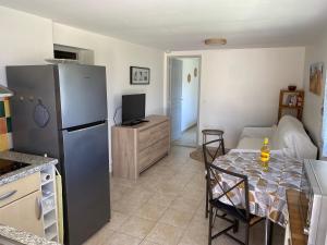 a kitchen with a table and a refrigerator in a room at T2 Rez de jardin 35 m2 in Balaruc-le-Vieux