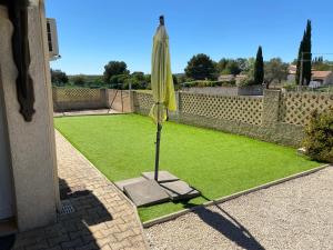 a yellow umbrella sitting on top of a lawn at T2 Rez de jardin 35 m2 in Balaruc-le-Vieux