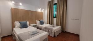 Una habitación de hotel con dos camas y un espejo. en Sabbia Suites El Muellito, en Famara