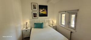 a bedroom with a white bed and two windows at Bastide avec grande piscine face à Sainte Victoire in Rousset +14 photos