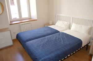 a bedroom with a bed with a blue comforter and two windows at Vut Casa de los Leales - Ávila in Ávila