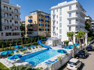 una piscina con sedie e ombrelloni di fronte agli edifici di ClubHotel Residence Cesenatico a Cesenatico
