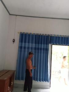 a man standing in front of a blue curtain at Homestay Saptia Dewi in Sengkol