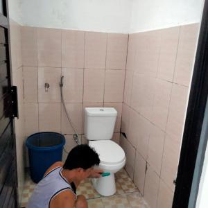 a man in a bathroom with a toilet at Homestay Saptia Dewi in Sengkol