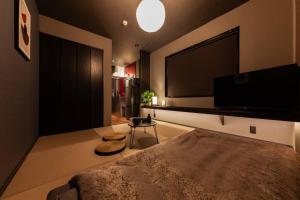 a bedroom with a flat screen tv and a bed at おやど紀伊国屋玉園町 in Asahimachi