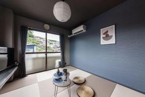 a room with a blue wall with a table and chairs at おやど紀伊国屋玉園町 in Asahimachi