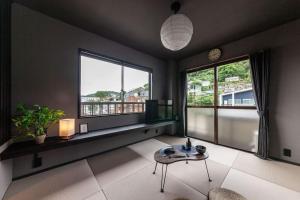 a living room with a table and two windows at おやど紀伊国屋玉園町 in Asahimachi