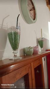 two glass vases on a wooden counter with a clock at Casa Emma in Cremolino +7 photos