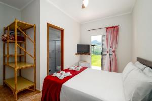 una camera da letto con un letto bianco con una coperta rossa di Pousada Linda Vista Socorro SP a Socorro Altre 101 foto