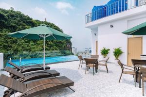 a patio with tables and chairs and an umbrella at Sand Hotel in Cat Ba