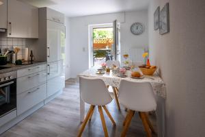 a kitchen with a table with white chairs and a tableablish at Ferienwohnung Caroline in Hemfurth-Edersee