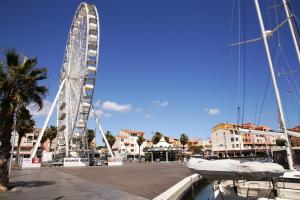 a ferris wheel next to a marina with boats at Centre port,vue panoramique,Clim,Balcon,wifi in Cap d'Agde