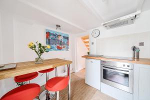 eine Küche mit einer Theke und roten Hockern darin in der Unterkunft Fowey, Cute Cottage in Fowey