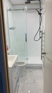 a white bathroom with a shower and a toilet at RUs Terraces in Kauri