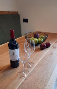 a bottle of wine and two wine glasses on a table at Il giardino di Anna - Appartamento 2 in Fai della Paganella