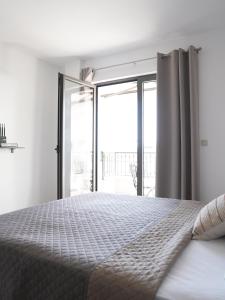 a white bedroom with a bed and a balcony at Apartman Bonaca in Pržno